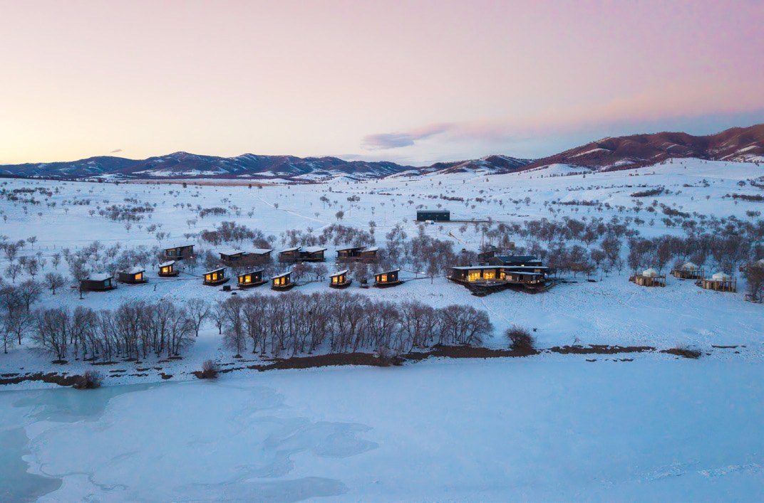 Butèle's warmly lit cabins in a snow-covered northern Mongolian valley